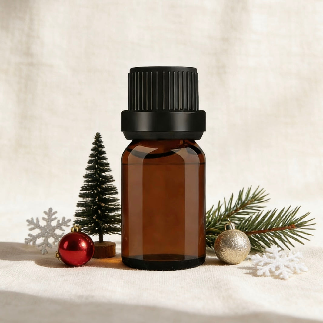 Amber glass essential oil bottle, surrounded by festive Christmas decor including a mini tree, baubles, and snowflakes, ideal for holiday-themed aromatherapy and candle making