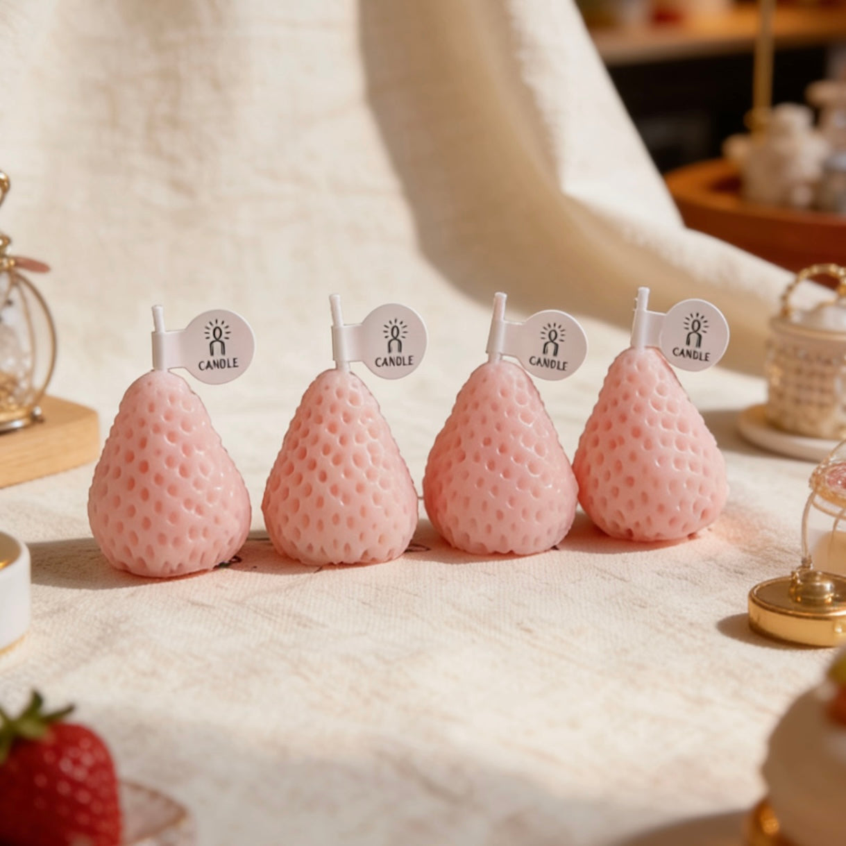 Set of pastel pink strawberry-shaped candles in a styled table setting