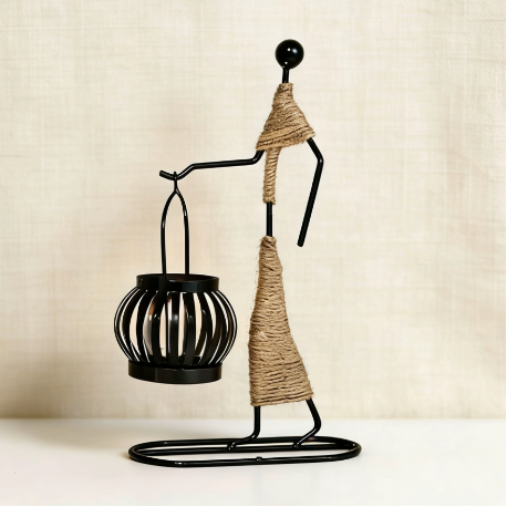 Abstract metal figure candle holder holding small lantern with rope