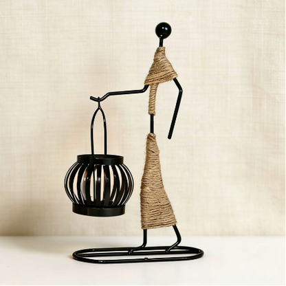 Abstract metal figure candle holder holding small lantern with rope