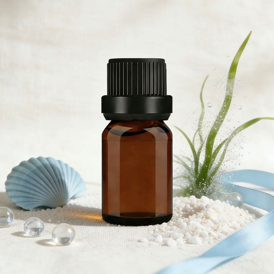 Amber glass essential oil bottle, surrounded by seashells, sea glass, and coastal-themed decor, ideal for aromatherapy and candle making