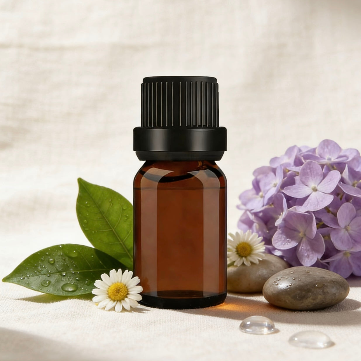 Amber glass essential oil bottle, surrounded by fresh daisies, hydrangeas, and smooth stones, ideal for aromatherapy, candle making, and natural wellness products