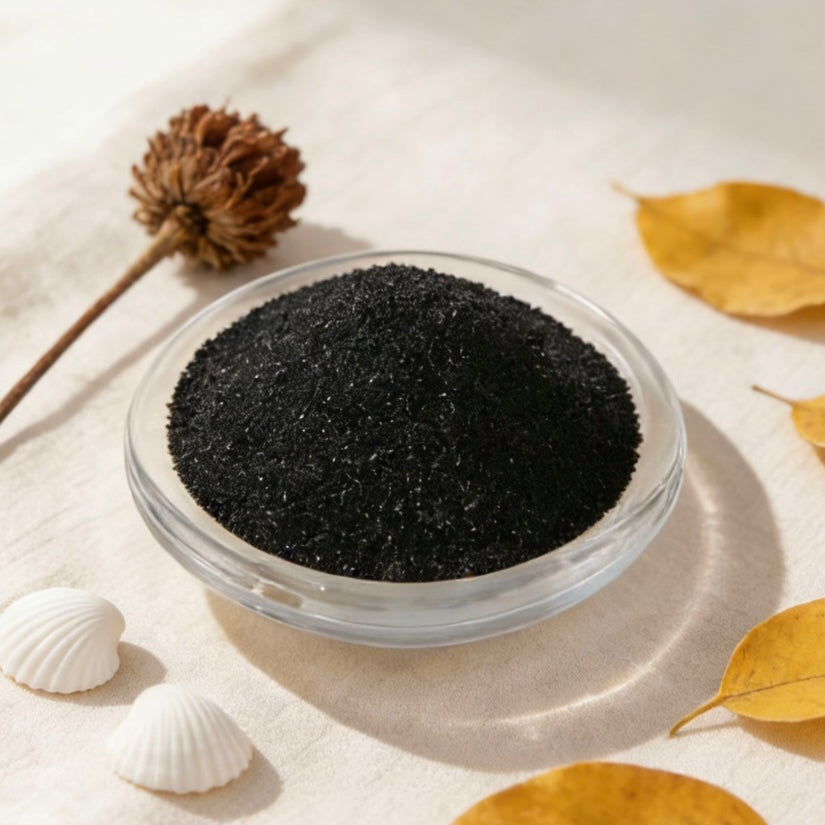 Black candle wax granules in a glass bowl, styled with dried flower, yellow autumn leaves and white seashells