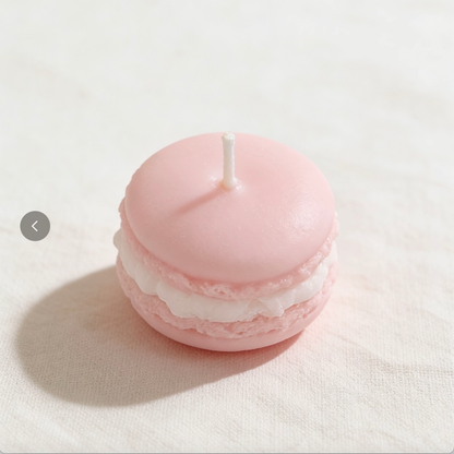 Blush pink macaron-shaped candle with white filling on a white linen background

