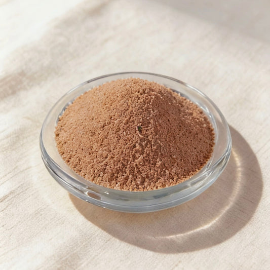 Brown candle wax powder in a clear glass bowl on a white linen background