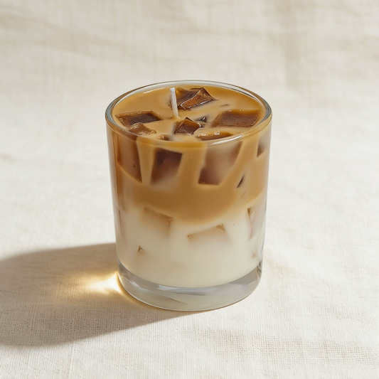 Layered iced coffee candle in a clear glass tumbler, featuring a white milk base, brown coffee layer, and realistic brown ice cube wax sculptures, with a cotton wick
