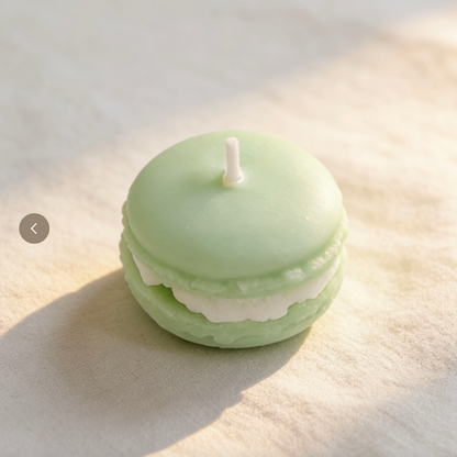 Mint green macaron-shaped candle with white filling on a light linen surface