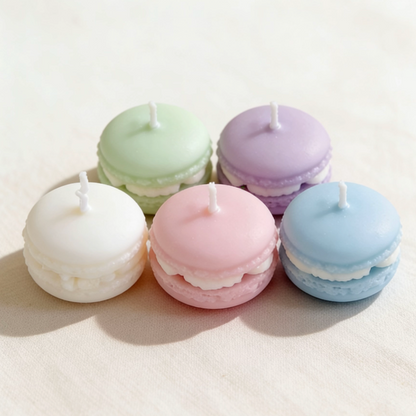 Pastel-colored macaron-shaped candles set in white, pink, blue, green and purple on a linen background