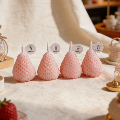 Set of pastel pink strawberry-shaped candles in a styled table setting
