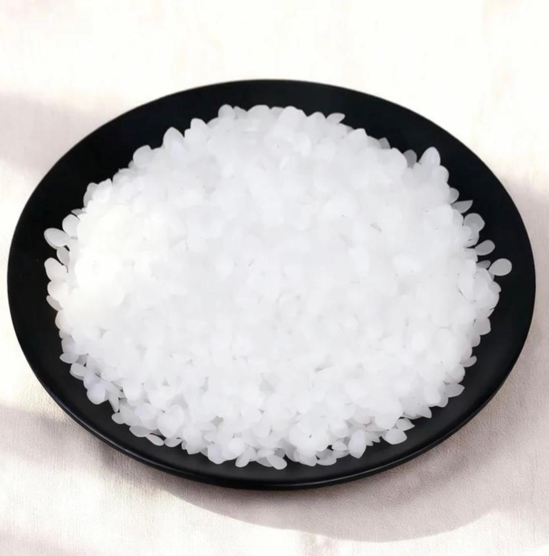 White translucent pellet wax in a black bowl, ideal for candle-making supplies