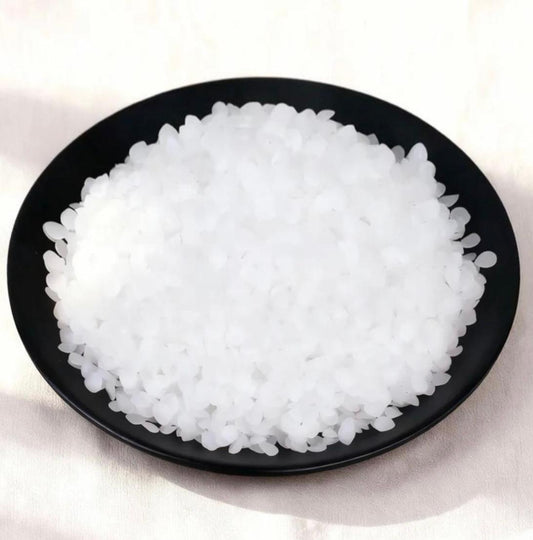 White translucent pellet wax in a black bowl, ideal for candle-making supplies