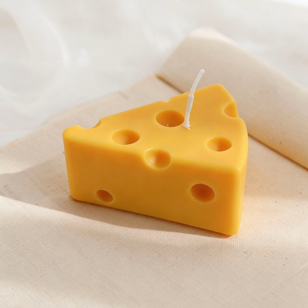 Realistic Swiss cheese wedge-shaped candle in bright yellow, with characteristic round holes and a cotton wick, displayed on a neutral linen background