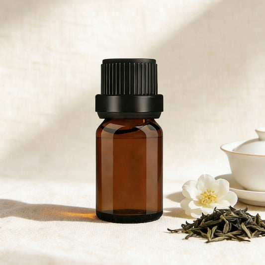Amber glass bottle of white tea-scented essential oil, surrounded by delicate jasmine flowers and loose tea leaves, ideal for creating calming, fresh aromatherapy blends, white tea-scented candles, and natural wellness products